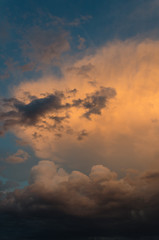 Dramatic clouds of thunderstorm in orange sunlight. Sunset on summer evening.
