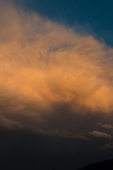 Fototapeta na wymiar Dramatic clouds of thunderstorm in orange sunlight. Sunset on summer evening.