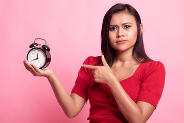 Angry young Asian woman point to a clock.