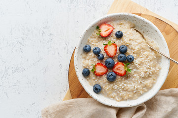 Oatmeal porridge rustic with berries, dash diet, on white wooden background top view - obrazy, fototapety, plakaty