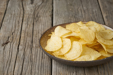 crisp in bowl, wooden background, closeup, copy space