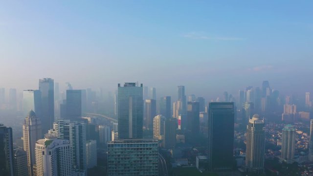 JAKARTA, Indonesia - June 17, 2019: Aerial landscape of silhouette of modern skyscrapers with morning haze. Shot in 4k resolution from a drone flying from right to left