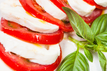 sliced mozzarella and tomato with basil close up