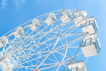 White Ferris wheel against clear blue sky. Close up