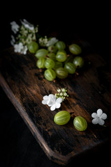 Gooseberry and flowers on a wooden Board, still life with berries in rustic style