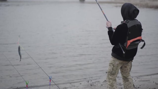 Young fisherman in the early morning catch scomber fish with spinning in river near the city. Fun or joke. Raffle or incredible.