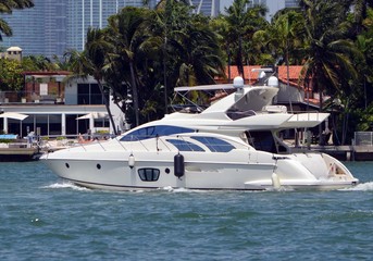 Fototapeta na wymiar Small white luxury motor yacht cruising past Rivo Alto island on the Florida Intra-Coastal Waterway