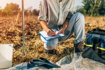 Soil Testing. Female Agronomists Taking Notes Outdoor - obrazy, fototapety, plakaty