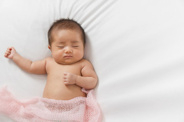 Adorable asian newborn baby in pink wrap sleeping on white blanket background.