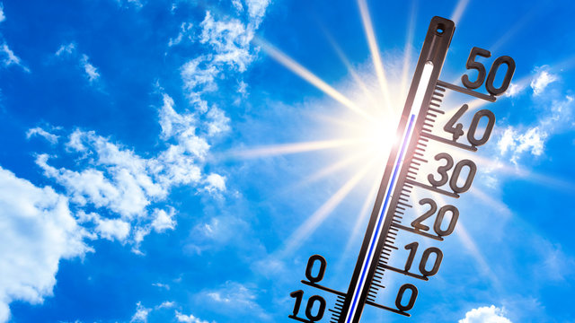 Hot summer or heat wave background, bright sun on blue sky with thermometer