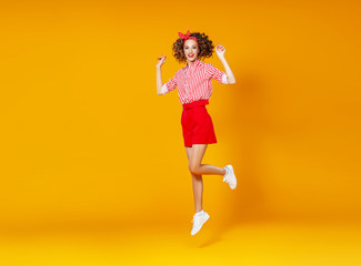 . concept happy emotional young woman in red  jumping   on yellow background