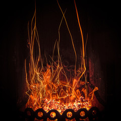 Fascinating spectacle of the bizarre magical dance of sparks and fire in the fireplace insert.