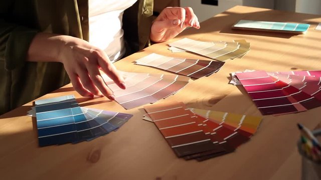 Young woman designer chooses from color palette and fabric samples the best for her client