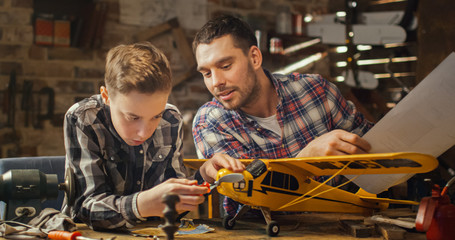 Father and son are modeling a toy airplane in a garage at home.