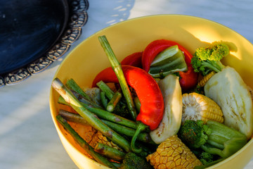 Corn, pepper and asparagus lie in a yellow bowl.  Concept - healthy food in the family.