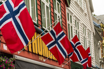 A row of Norwegian Flags flying on traditional buildings.