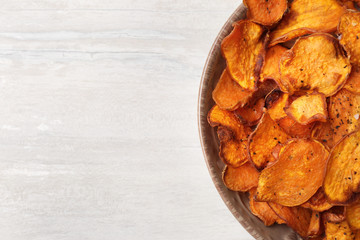 Plate of sweet potato chips on light table, top view. Space for text
