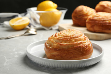 Plate with tasty bun on stone table, space for text. Fresh from oven