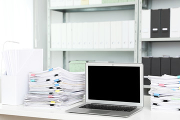 Laptop and documents on desk in office. Space for text