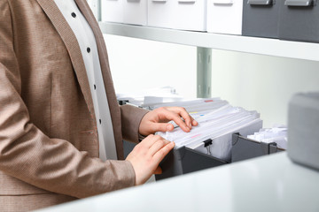 Woman taking documents from folder in archive, closeup