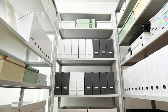 Folders and boxes with documents on shelves in archive