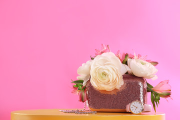 Obraz na płótnie Canvas Elegant handbag with spring flowers on table against pink background, space for text