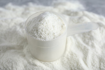 Scoop and pile of protein powder on table, closeup