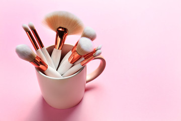 Professional makeup brushes in cup on pink background. Space for text - Powered by Adobe