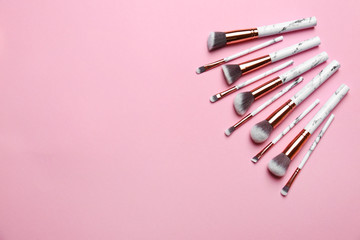 Different makeup brushes on pink background, flat lay. Space for text