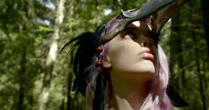 shaman with long purple hair takes off bone mask and looks