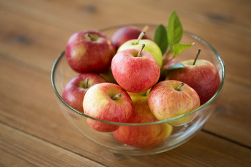 fruits, food and harvest concept - ripe apples in glass bowl on wooden table