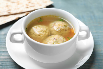Bowl of Jewish matzoh balls soup on color wooden table