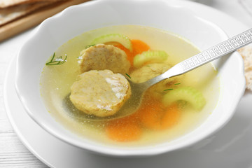 Bowl of Jewish matzoh balls soup on table, closeup