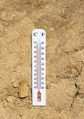 thermometer on dry earth in cracks. hot weather concept, high temperature, dry soil on background....