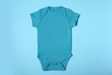 Cute baby onesie on color background, top view