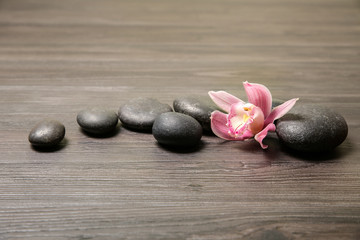 Fototapeta na wymiar Spa stones with orchid flower on wooden background