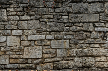 Alte Natursteinmauer aus grauen und gelblichen Steinen in unterschiedlichen Größen