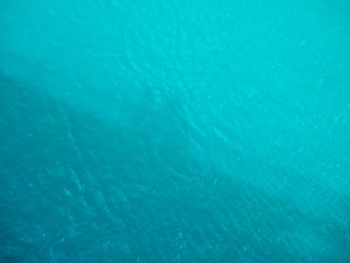 Fototapeta na wymiar shadows of people on a turquoise water surface