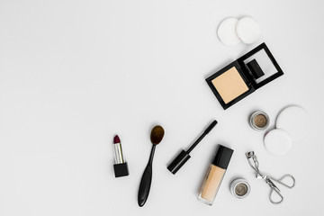 Obraz premium Cosmetic sponges; compact powder; foundation; lipstick eyeshadow; eyelash curler and brushes on white background