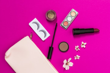 Obraz na płótnie Canvas Spring blossom; eyelashes; eyeshadow; lipstick; mascara brush and blossom with pink makeup bag on pink background