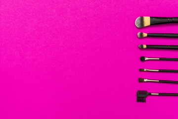 Row of makeup brushes with copy space for writing the text on pink background