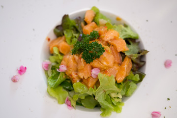 Spicy salmon salad served on fresh green oak