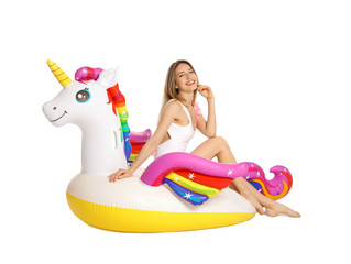 Beautiful young woman in stylish bikini with unicorn inflatable ring on white background