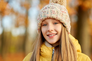 childhood, season and people concept - portrait of happy girl at autumn park