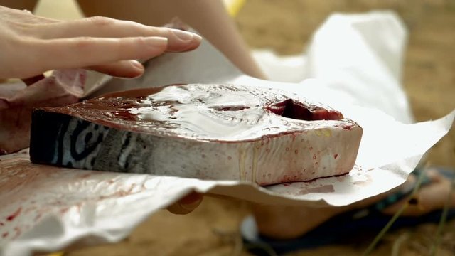 Close-up shot of female hand rubbing olive oil to a fillet of tuna fish. Slow motion. HD