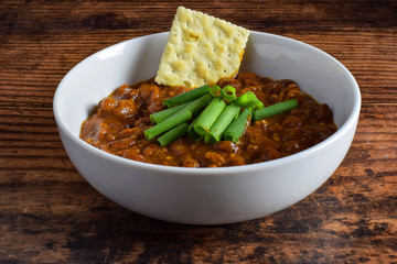bowl of chili with crackers and green onions