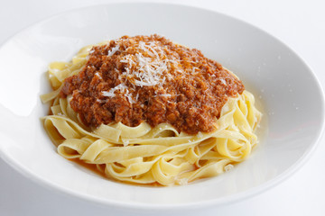 Delicious Fresh Fettuccine Pasta with Bolognese sauce and sprinkled with Permesan Cheese isolated on white plate and white background