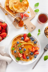 pancakes with blueberry strawberry honey and nuts for breakfast