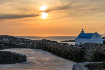 The sunset, the blue roof of the Greek Orthodox Church, the stone wall.