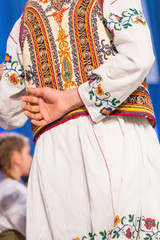 Young Romanian dancer hold hand on his back while perform a folk dance in traditional folkloric costume. Folklore of Romania